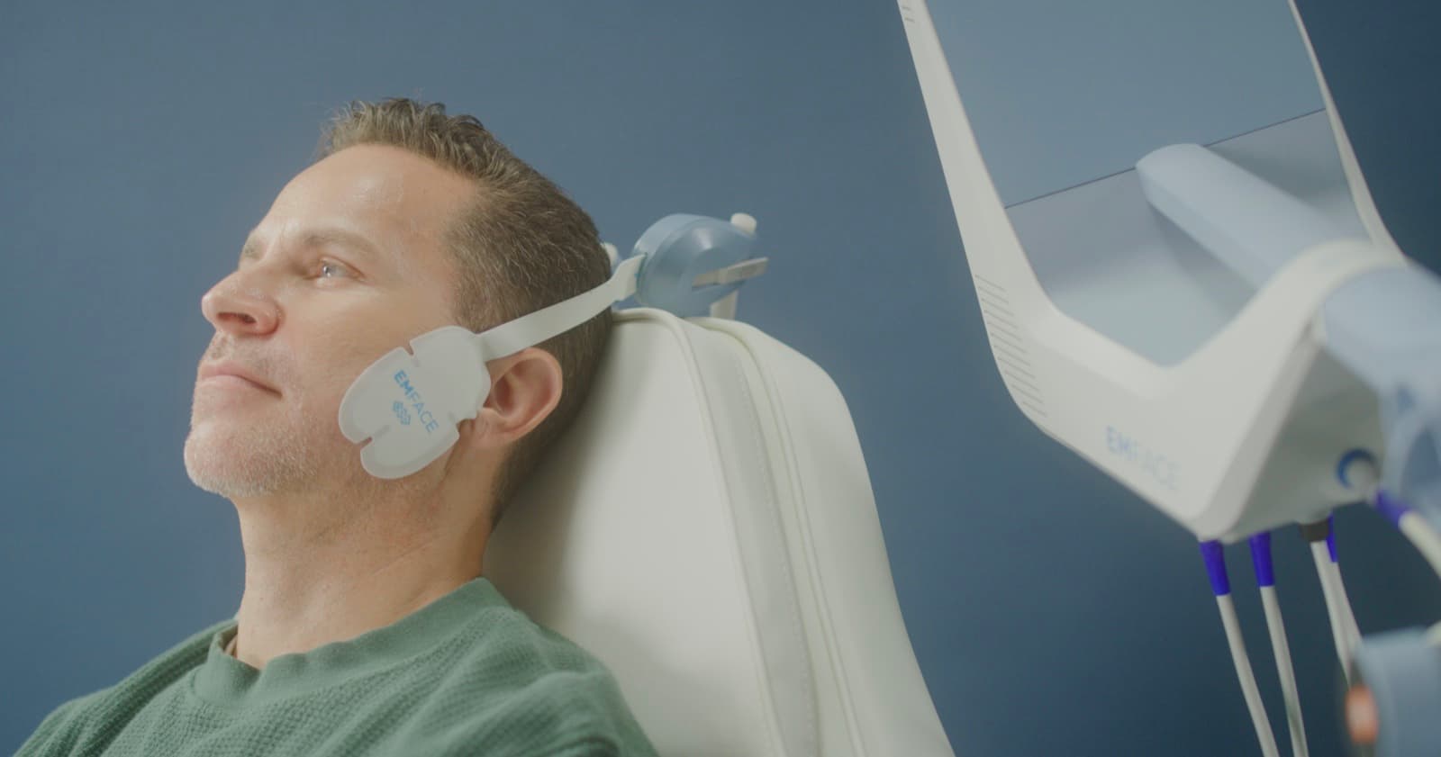 Male patient mid-EMFACE® session — applicator pads in place